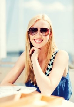 summer holidays and vacation - girl in shades in cafe on the beach