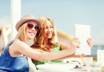 summer holidays, vacation and technology - girls taking photo with tablet pc in cafe on the beach