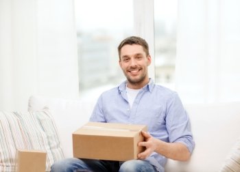 post, home and lifestyle concept - smiling man with cardboard boxes at home