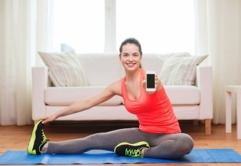 fitness, home, technology and diet concept - smiling teenage girl streching on floor with smartphone at home