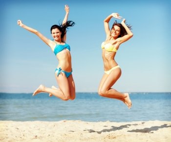 summer holidays and vacation concept - beautiful girls in bikini jumping on the beach