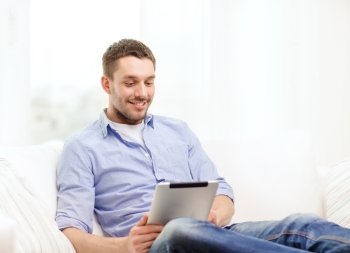 technology, home and lifestyle concept - smiling man working with tablet pc computer at home