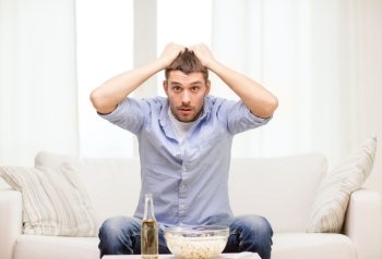 sports, happiness and people concept - sad man watching sports on tv and supporting team at home