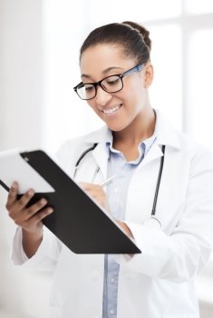 healthcare and medical concept - smiling african female doctor with prescription in hospital