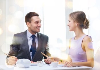 restaurant, couple and holiday concept - smiling couple eating sushi at restaurant
