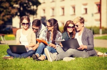 summer, internet, education concept - group of students or teenagers with laptop, notebooks, files and folders