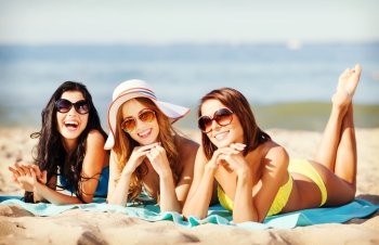summer holidays and vacation - girls in bikinis sunbathing on the beach