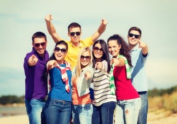 summer, holidays, vacation, happy people concept - group of friends having fun on the beach and pointing at you