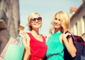 sale and tourism, happy people concept - beautiful women with shopping bags and credit card in the ctiy