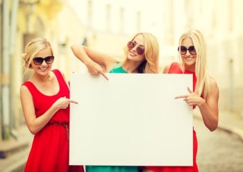 summer holidays, , travel, tourism and advertisement concept - three happy blonde women with blank white board in the city