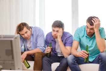 friendship, sports and entertainment concept - sad male friends with beer watching sports on tv at home