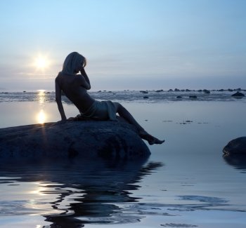 silhouette image of topless lady on the rock