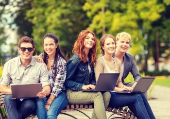 summer holidays, education, campus, technology and teenage concept - group of students or teenagers with laptop computer
