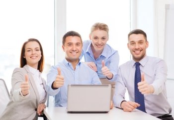 business and office concept - smiling business team working with laptop computer in office showing thumbs up