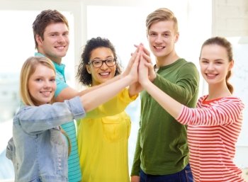 education and friendship concept - five smiling students giving high five at school