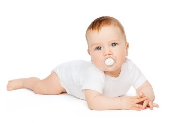 child and toddler concept - smiling baby lying on floor with dummy in mouth