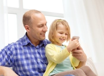 family, children, parenthood, technology and internet concept - happy father and daughter with smartphone at home