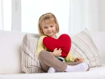 child, love and happiness concept - smiling little girl with red heart at home
