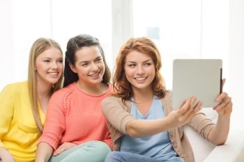 friendship, technology and internet concept - three smiling teenage girls taking picture with tablet pc computer camera at home