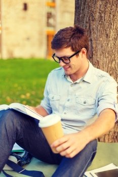 education, campus and people concept - smiling teenager in eyeglasses reading book with take away coffee
