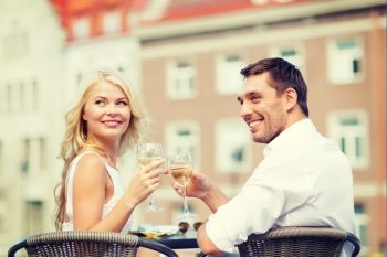 summer holidays and dating concept - smiling couple drinking wine in cafe in the city