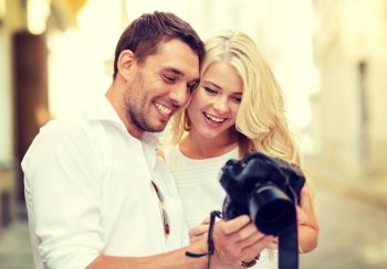 summer holidays and dating concept - smiling couple with photo camera in the city