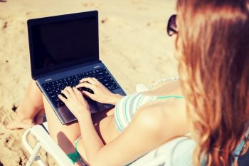 summer holidays, vacation, technology and internet - girl looking at laptop on the beach chair