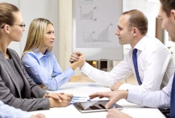 business and office concept - businesswoman and businessman arm wrestling during meeting in office