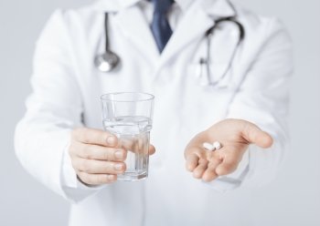 picture of doctor hands giving white pills and glass of water