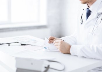 close up of male doctor writing prescription paper