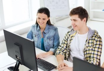 education, technology, school and people concept - two smiling students having discussion in computer class at school