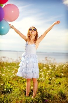 summer holidays, celebration, children and people concept - happy girl waving hands with colorful balloons outdoors