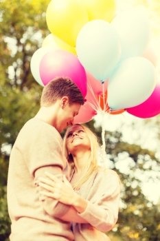 summer holidays, celebration and dating concept - smiling couple with colorful balloons in the park