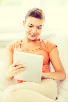 home, technology and internet - woman sitting on the couch with tablet pc at home
