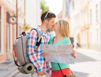 travel, vacation, love and friendship concept - smiling couple with map and backpack in city