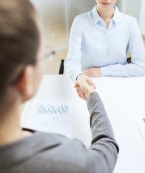 business and office concept - two calm businesswoman shaking hands in office