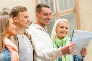 travel, vacation and friendship concept - group of smiling friends with city map exploring city