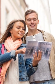 travel, vacation, love and friendship concept - smiling couple with city guide exploring town