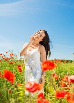 happiness, nature, summer, vacation and people concept - smiling young woman with closed eyes on poppy field
