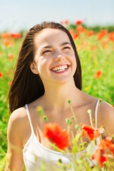 happiness, nature, summer, vacation and people concept - laughing young woman on poppy field