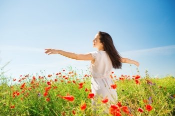 happiness, nature, summer, vacation and people concept - smiling young woman on poppy field