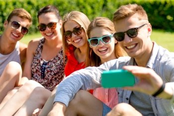 friendship, leisure, summer, technology and people concept - group of laughing friends with smartphone making selfie in park