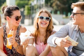 friendship, leisure, summer and people concept - group of smiling friends in sunglasses sitting with food on city square