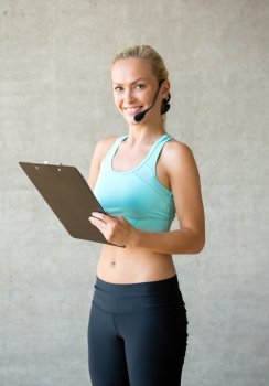 fitness, sport and diet concept - beautiful athletic woman with clipboard in gym