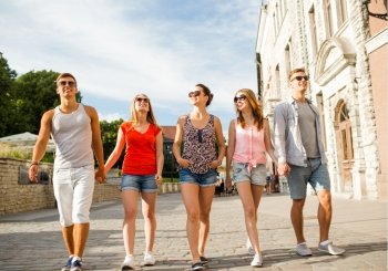 friendship, leisure, summer, gesturer and people concept - group of smiling friends walking and holding hands in city