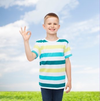 childhood, accomplishment, gesture and people concept - smiling little boy in casual clothes making OK gesture over natural background