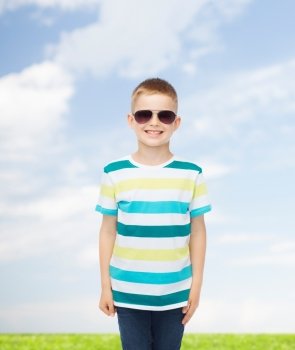 happiness, summer, childhood, nature and people concept - smiling cute little boy in sunglasses over natural background