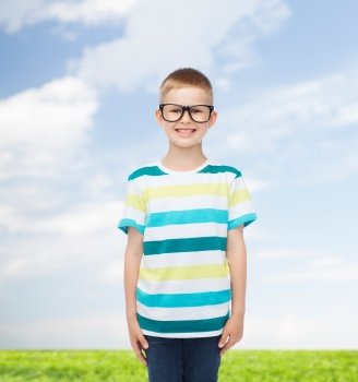 vision, education, nature and school concept - smiling little boy in eyeglasses over natural background