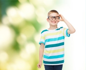 vision, education, ecology and school concept - smiling little boy in eyeglasses over green background