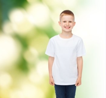 advertising, ecology, people and childhood concept - smiling little boy in white blank t-shirt over green background